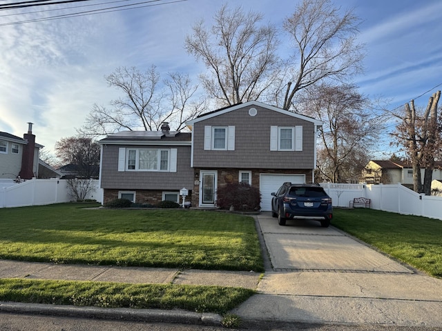 tri-level home with a garage, a front yard, concrete driveway, and fence