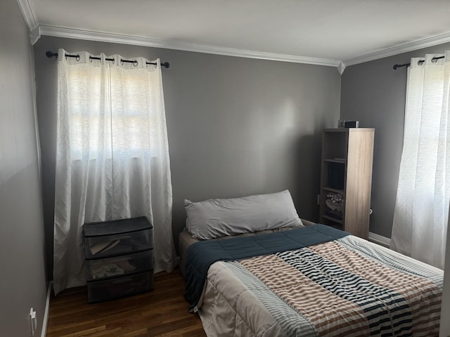 bedroom with wood finished floors, baseboards, and ornamental molding