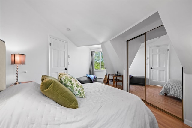 bedroom with a closet, vaulted ceiling, and wood finished floors