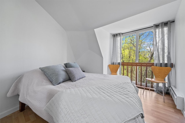 bedroom with lofted ceiling, baseboards, and light wood-type flooring