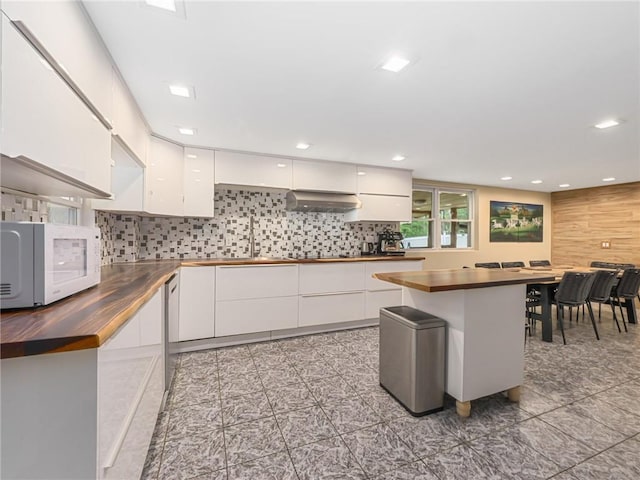 2 Hollowaty Kosak Rd, Glen Spey, NY 12737 - kitchen with white microwave, backsplash, white cabinetry, under cabinet range hood, and wooden counters