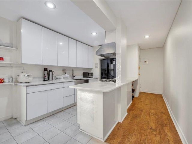 kitchen with modern cabinets, stainless steel microwave, white cabinets, and freestanding refrigerator