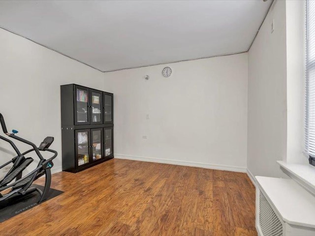 workout area with baseboards and wood finished floors