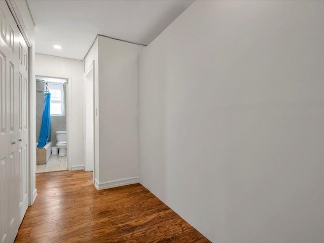 hall with light wood finished floors, baseboards, and recessed lighting