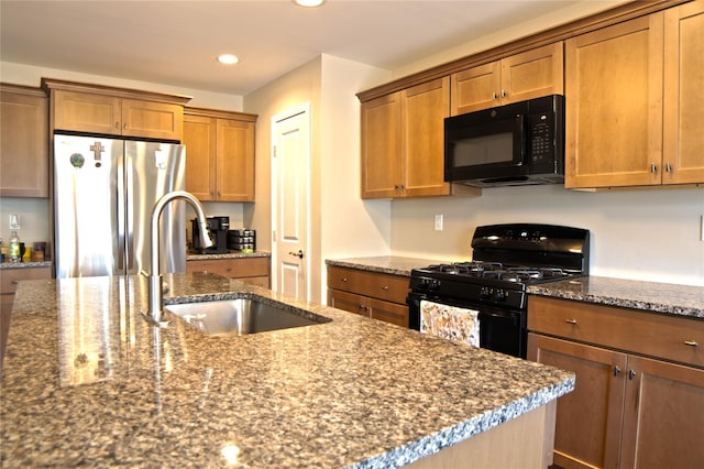 kitchen with brown cabinets, a sink, black appliances, dark stone countertops, and recessed lighting