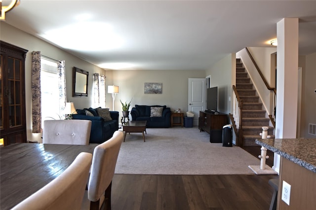 living room with dark wood-style flooring, stairs, and visible vents