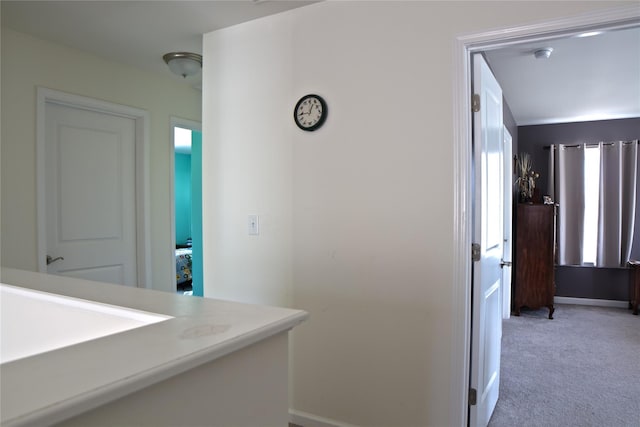 hallway with baseboards and light carpet
