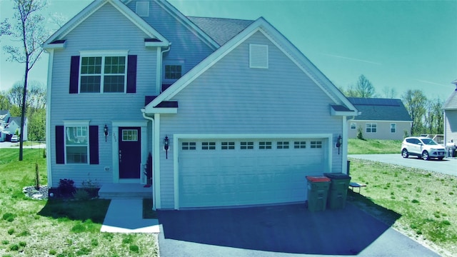 view of front of home featuring an attached garage, a front lawn, and driveway