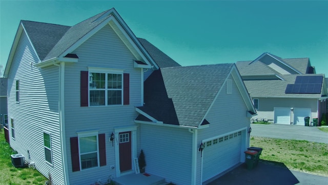 view of front of property featuring roof with shingles, a front lawn, central AC, and driveway