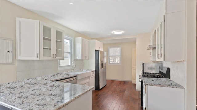 kitchen featuring stainless steel appliances, backsplash, glass insert cabinets, and light stone counters