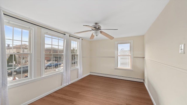 unfurnished room with a baseboard heating unit, wood finished floors, baseboards, and ceiling fan