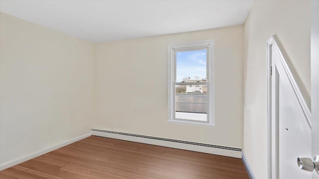 unfurnished room with a baseboard radiator, baseboards, and wood finished floors