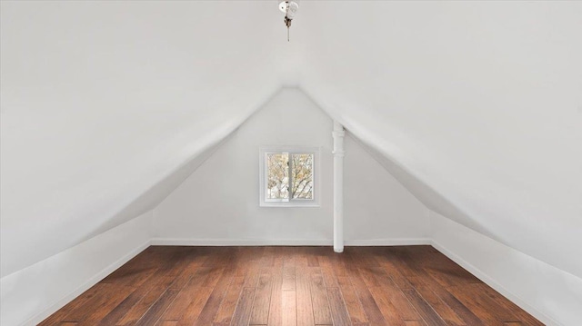 additional living space featuring lofted ceiling, baseboards, and dark wood finished floors
