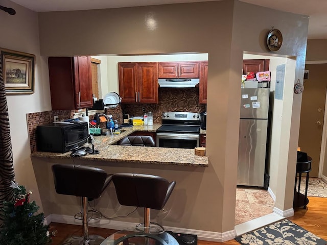 7 Everit Ave Unit B11, Hewlett, NY 11557 - kitchen featuring light stone counters, under cabinet range hood, stainless steel appliances, a sink, and tasteful backsplash