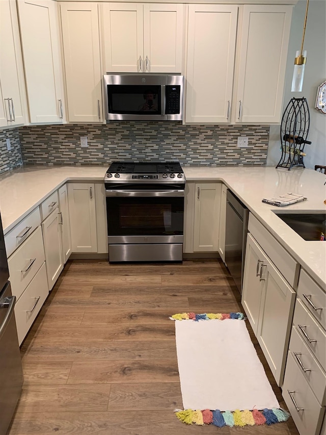 2300 Fox Hill Dr Unit 1101, Baiting Hollow, NY 11933 - kitchen featuring stainless steel appliances, light countertops, wood finished floors, and decorative backsplash
