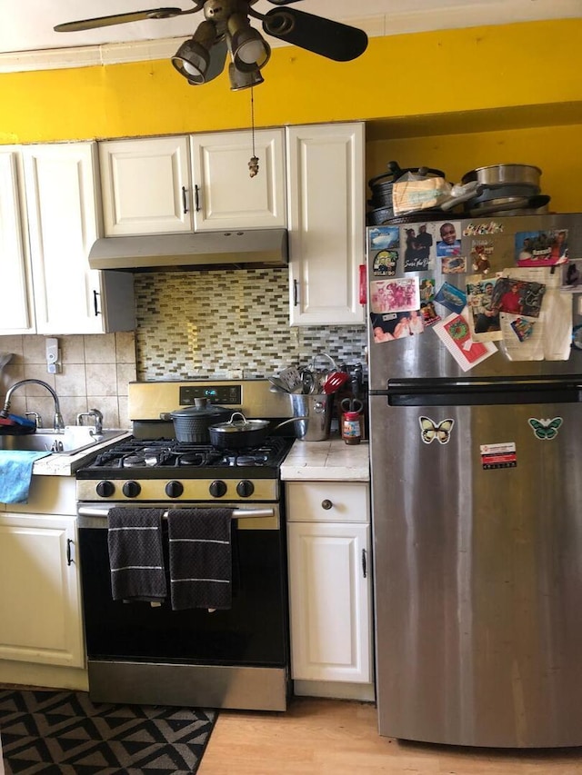 kitchen featuring white cabinets, stainless steel appliances, a ceiling fan, light countertops, and under cabinet range hood