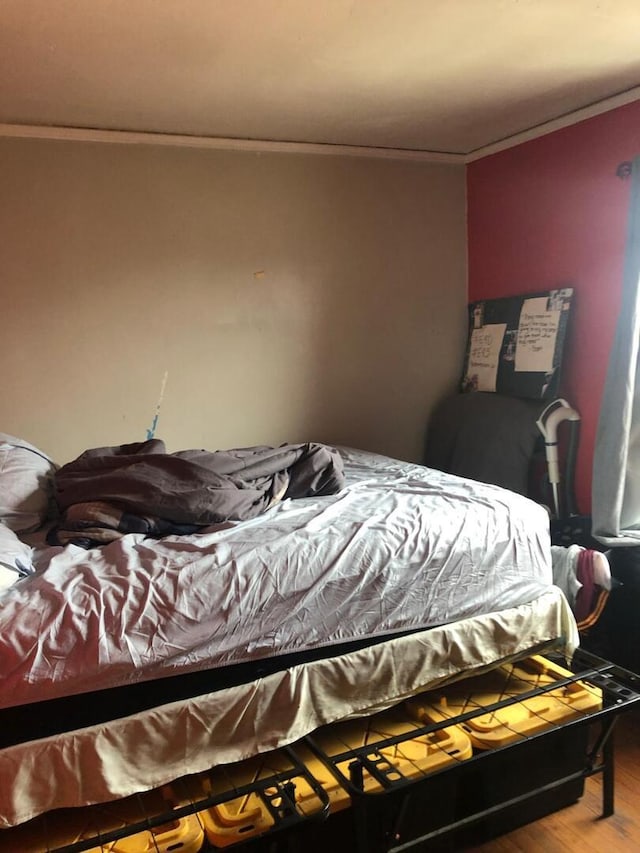 bedroom with wood finished floors and crown molding