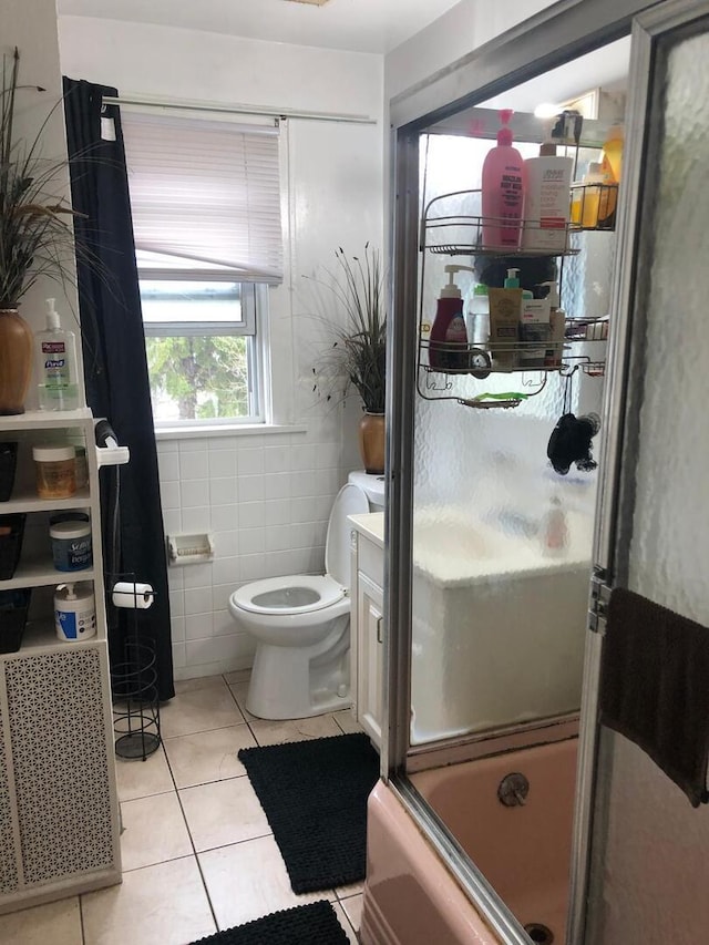 full bath featuring toilet, tile patterned floors, shower / bath combination with glass door, and tile walls
