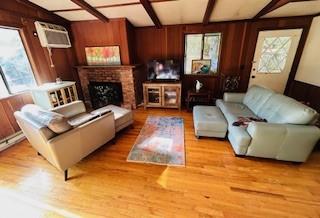 9 Cardiff, Rock Hill, NY 12775 - living room featuring wood walls, a fireplace, wood finished floors, and beam ceiling