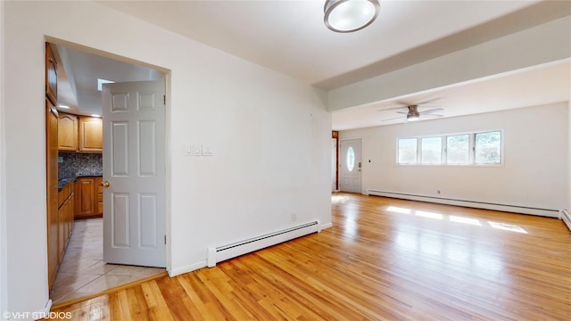 spare room with ceiling fan, a baseboard heating unit, and light wood finished floors