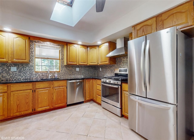 kitchen with wall chimney exhaust hood, light tile patterned floors, a sink, appliances with stainless steel finishes, and backsplash
