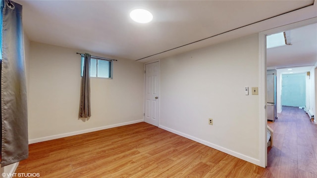 unfurnished room with baseboards and light wood-style flooring