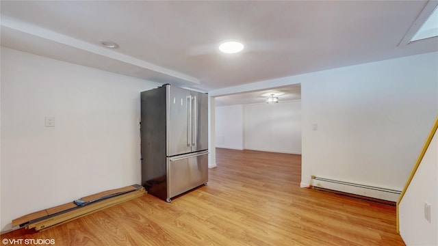 empty room featuring baseboards, light wood-style flooring, and a baseboard radiator