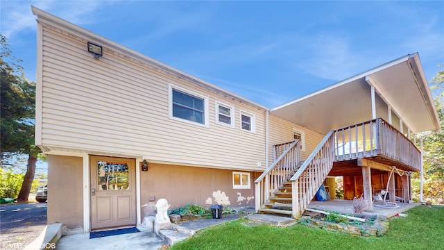 back of property featuring a wooden deck, stucco siding, and stairway