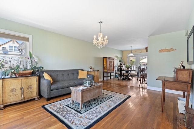 living area featuring an inviting chandelier, wood finished floors, and baseboards