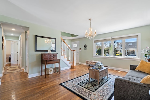 living area with an inviting chandelier, wood finished floors, stairs, and baseboards