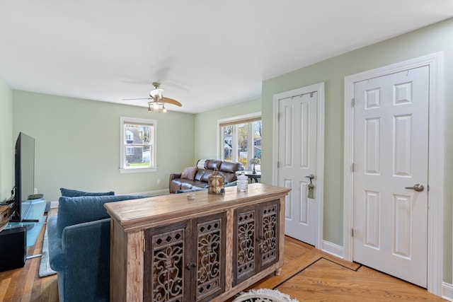 interior space featuring light wood finished floors, baseboards, and ceiling fan