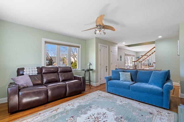 living area featuring wood finished floors, a healthy amount of sunlight, stairs, and ceiling fan