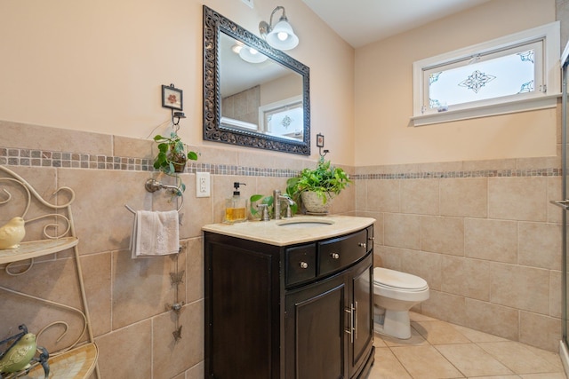 full bathroom with toilet, tile walls, wainscoting, tile patterned flooring, and vanity
