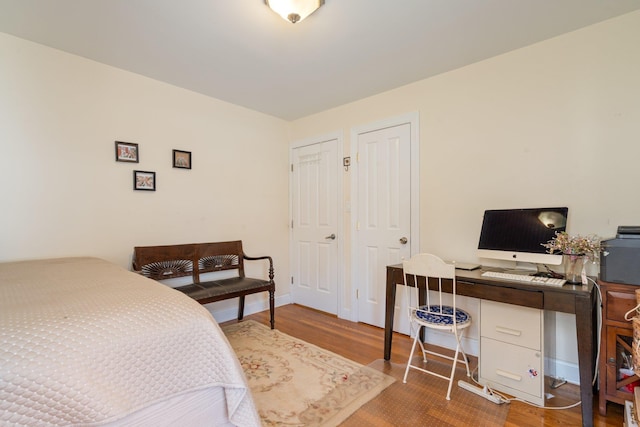bedroom featuring multiple closets, baseboards, and wood finished floors