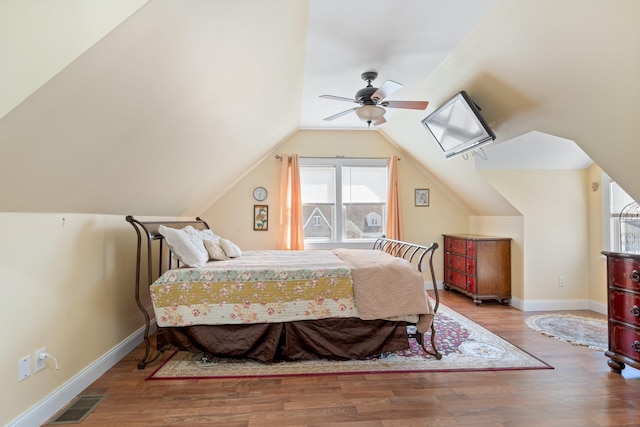 bedroom featuring a ceiling fan, wood finished floors, baseboards, lofted ceiling, and visible vents