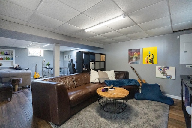 living room with wood finished floors, electric panel, a drop ceiling, and baseboards