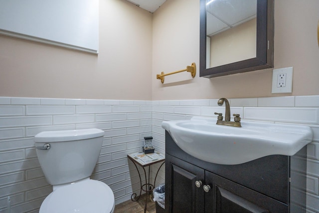 bathroom featuring tile walls, a wainscoted wall, vanity, and toilet