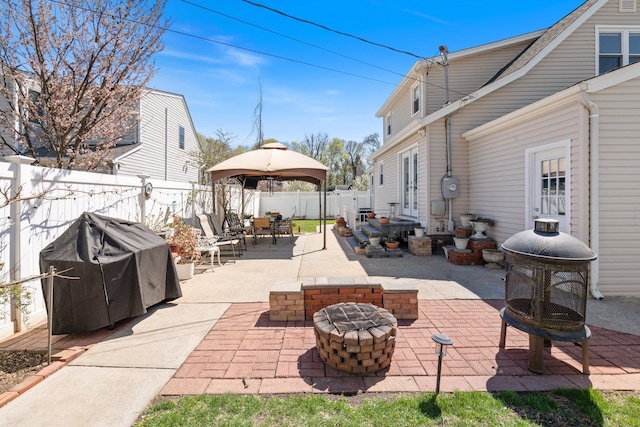 view of patio / terrace with a grill, a fenced backyard, outdoor dining space, an outdoor fire pit, and a gazebo