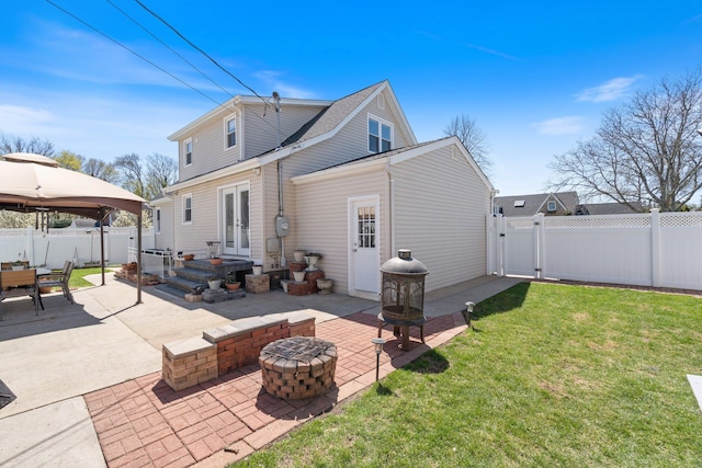 rear view of house featuring a fire pit, a patio area, a lawn, and french doors