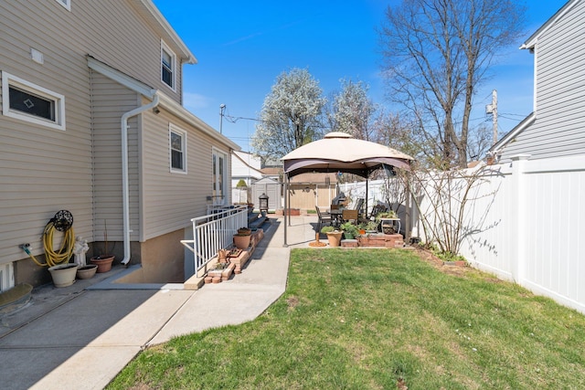 view of yard featuring an outbuilding, a fenced backyard, a gazebo, a patio area, and a shed