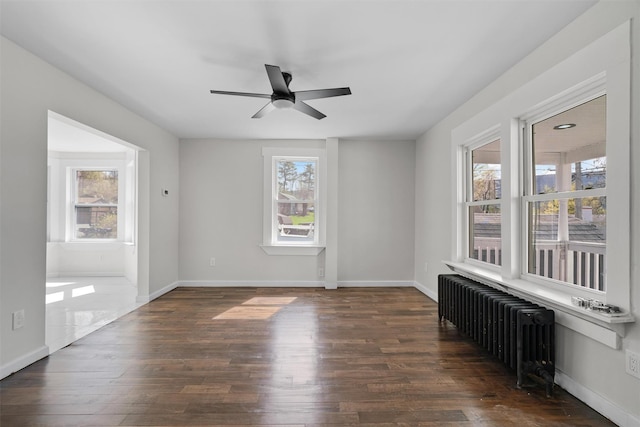 spare room featuring a healthy amount of sunlight, dark wood-style floors, and radiator