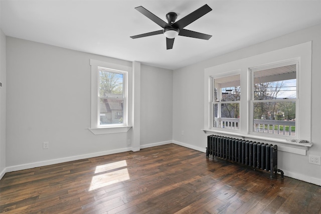 spare room featuring radiator heating unit, baseboards, a ceiling fan, and wood finished floors
