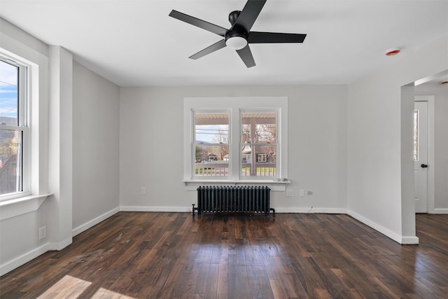 spare room with radiator, a wealth of natural light, wood finished floors, and ceiling fan