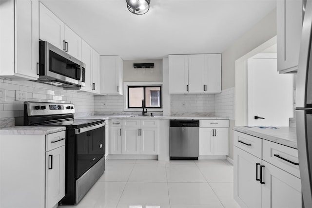 kitchen with white cabinets, stainless steel appliances, a sink, tasteful backsplash, and light countertops