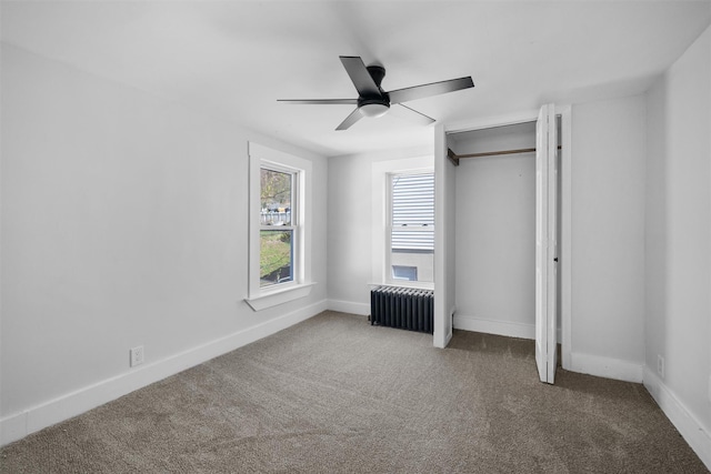 unfurnished bedroom featuring radiator heating unit, carpet floors, a ceiling fan, and baseboards