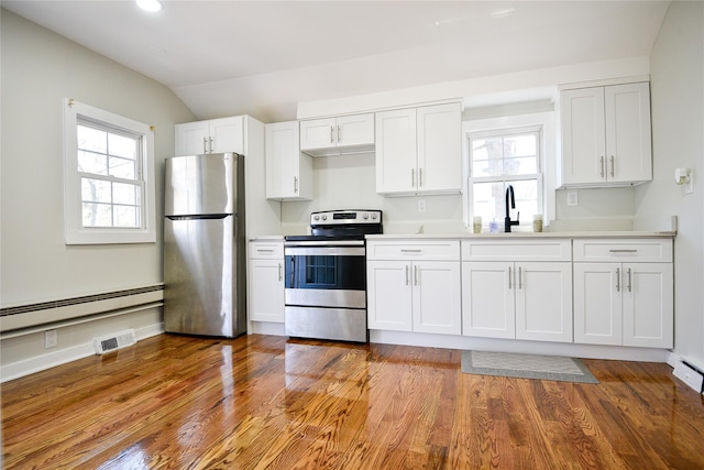 129 Locust Dr, Mastic Beach, NY 11951 - kitchen with appliances with stainless steel finishes, baseboard heating, white cabinets, vaulted ceiling, and a sink