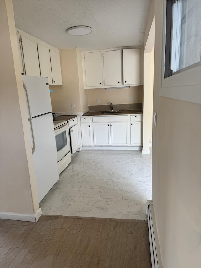 kitchen with marble finish floor, white appliances, baseboard heating, white cabinets, and a sink