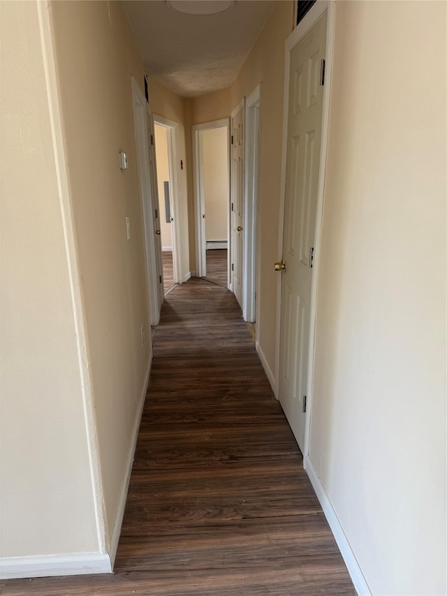 corridor with baseboards and dark wood-style flooring