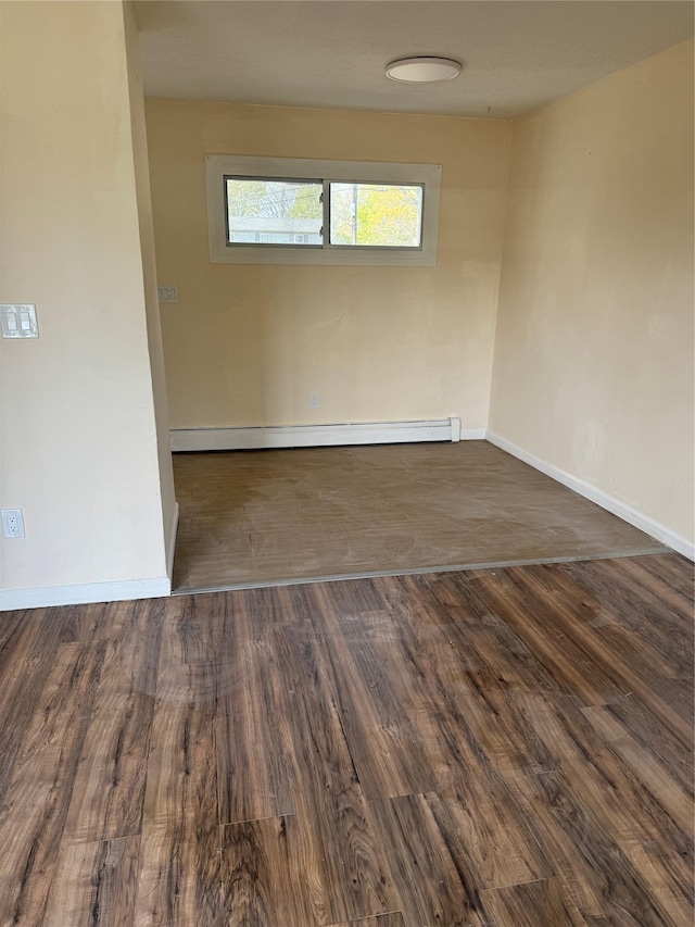 unfurnished room featuring baseboards, a baseboard heating unit, and wood finished floors