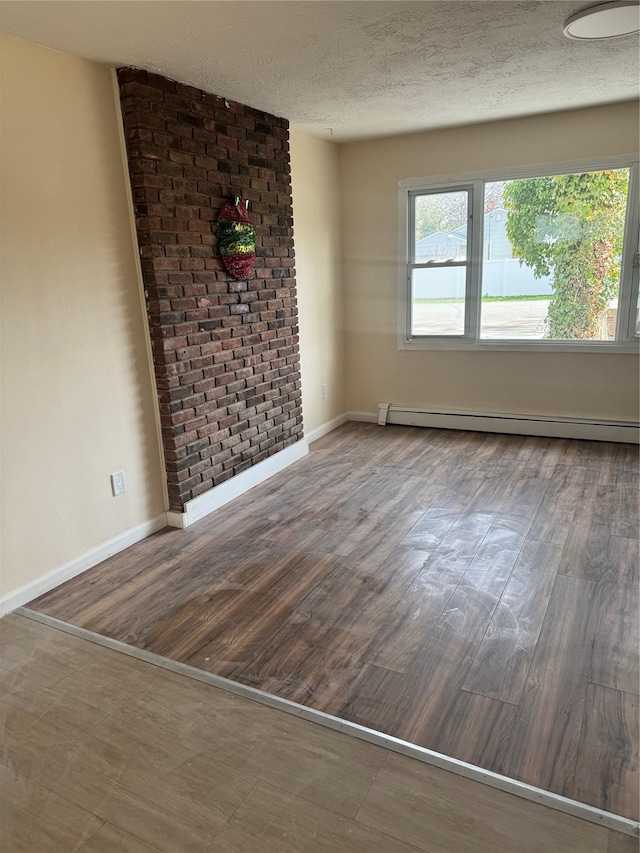 spare room featuring baseboards, a baseboard radiator, a textured ceiling, and wood finished floors